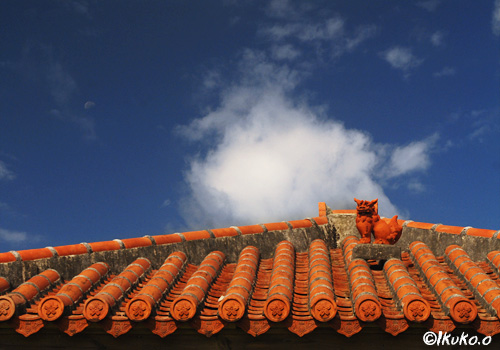 赤瓦屋根の上のシーサーと雲