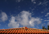 赤瓦屋根の上のシーサーと雲